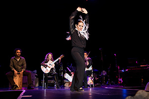 Woman in black with her hands up and a band behind her.