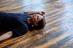 Woman laying on wooden floor.