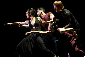 Four people looking to the left with outstretched arms in a dramatic pose.