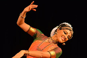 A woman smiling in a pose with black background.