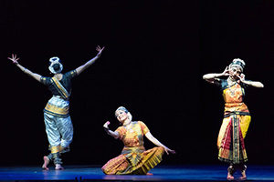Three women in South Indian attire in poses on stage.